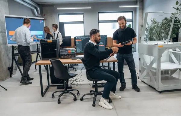 İşbirliği ve iletişim kavramı. Ofiste 3D yazıcının yanında insanlar var..