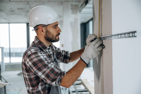 View from the side. A man is renovating an unfinished room.
