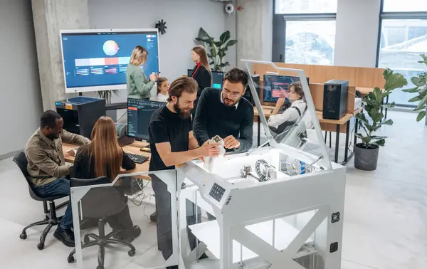 Modern teknoloji. Ayakta. Ofiste 3D yazıcının yanında insanlar var..