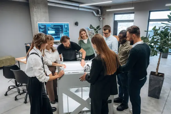 Ofisteki 3D yazıcının etrafında bir grup insan duruyor..