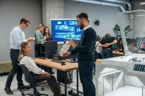 İşbirliği ve iletişim kavramı. Ofiste 3D yazıcının yanında insanlar var..