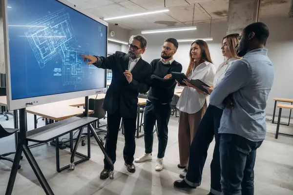 Bina planı ekranda. Bir grup ofis çalışanı içeride birlikte..