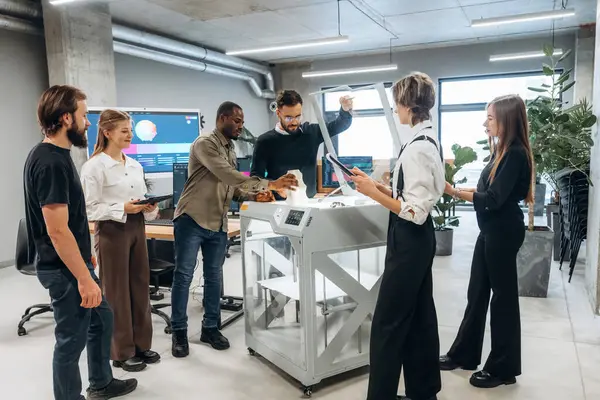 Çalışanlar bir arada. Ofiste 3D yazıcının yanında insanlar var..