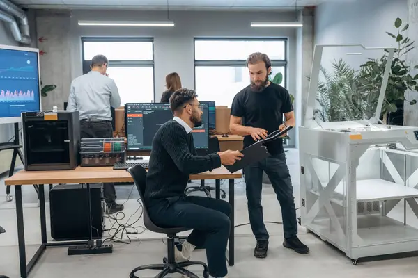 İşbirliği ve iletişim kavramı. Ofiste 3D yazıcının yanında insanlar var..