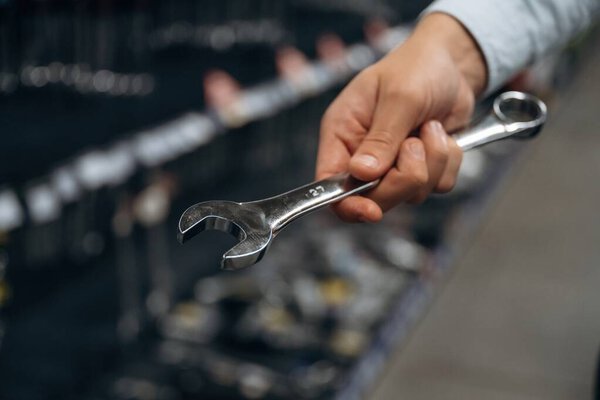 Wrench in hand. Detailed close up view of man's hand in the hardware store.