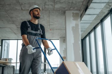 Eşyaları taşıyorum. Bir adam bitmemiş bir odayı yeniliyor..