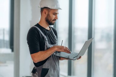 Kablosuz cihaz, dizüstü bilgisayarı tutuyor. Bir adam bitmemiş bir odayı yeniliyor..