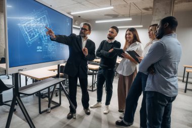 Bina planı ekranda. Bir grup ofis çalışanı içeride birlikte..