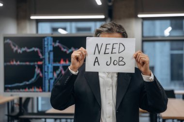 İş ararken, pankartı mesajla tutarken. Kıdemli adam modern ofiste..