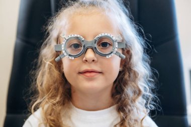 Küçük kız göz doktorunun dolabında görüşünü kontrol ediyor..