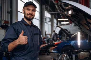 Başparmak yukarı, her şey halledilecek. Araba tamirhanesinde çalışan bir tamirci..