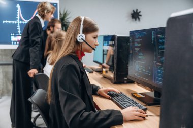 Bilgisayarların başında oturuyor. Tasarımcı takımı ofiste birlikte..