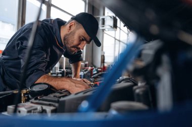 Nakil aracı tamir ediliyor. Araba tamirhanesinde çalışan bir tamirci..