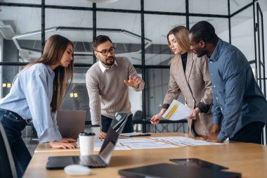 Konuşuyoruz, plan hakkında konuşuyoruz. Profesyonel işçiler modern ofiste birlikte çalışıyorlar..
