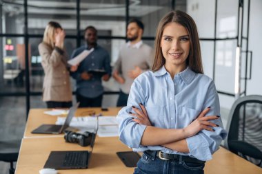 Neşeli kadın ayakta duruyor. Profesyonel işçiler modern ofiste birlikte çalışıyorlar..