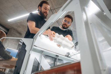 3D yazıcıyı gösteriyor. Ofiste insanlar var..