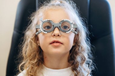 Sağlık sigortası gebeliği, oturma, arama. Küçük kız göz doktorunun dolabında görüşünü kontrol ediyor..