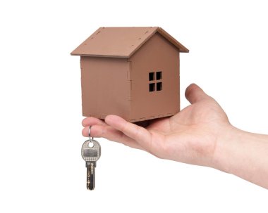 Beyaz arka planda el ele tutuşan anahtarlar ve ahşap ev