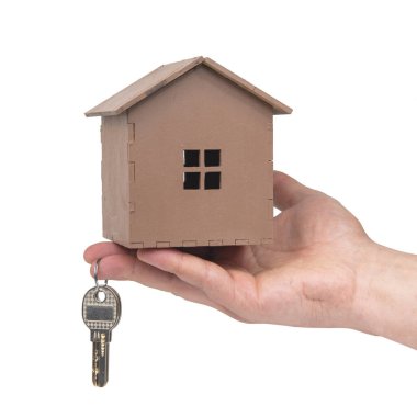 Beyaz arka planda el ele tutuşan anahtarlar ve ahşap ev