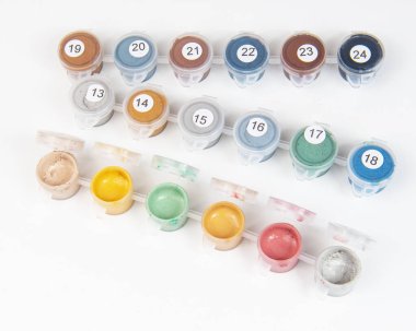 Boyalı bir tuvalde boya dolu küçük kavanozlar. Sayılarla boyamak. Parlak ve renkli..