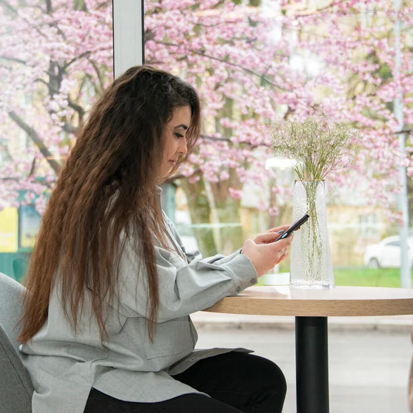 Güzel bir kadın akıllı telefonu iş için kullanıyor, online alışveriş, para transferi, finans, internet bankacılığı. Kahve dükkanında.