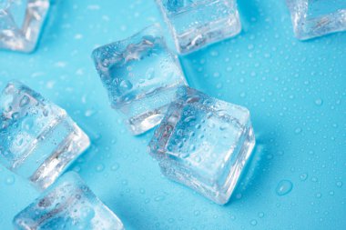 Su damlaları olan buz küpleri mavi arkaplana saçılmış, üst manzara.