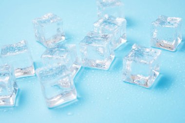 Su damlaları olan buz küpleri mavi arkaplana saçılmış, üst manzara.