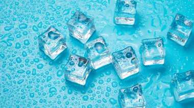 Mavi zemin üzerinde erimiş su damlaları olan buz küpleri..