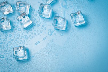 Su damlaları olan buz küpleri mavi arkaplana saçılmış, üst manzara