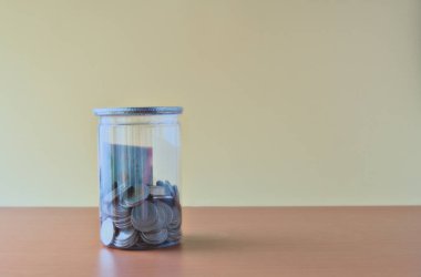 Sarı arka planda bir kavanozda Tayland parası yığını. Gelecek için para biriktirme kavramı.