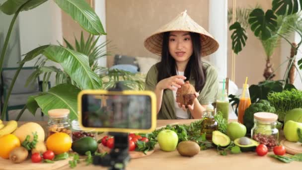 社交媒体和内容创建者在未来从事新的工作 戴传统锥形礼帽的美丽的亚洲博客作者用椰子做早餐 并为在线频道现场直播录像 — 图库视频影像