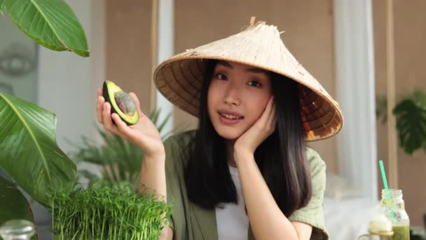 Hermosa Mujer Asiática Sombrero Cónico Tradicional Sosteniendo Aguacate Sentado Mesa — Vídeo de stock
