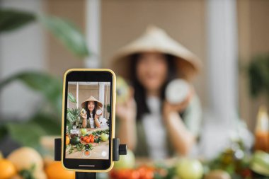 Neşeli Asyalı kadın vlogger pişiriyor, takipçilerine canlı yayın yapıyor, avokado, hindistan cevizi ve diğer malzemeleri kullanarak kahvaltıyı nasıl hazırlayacağını gösteriyor..