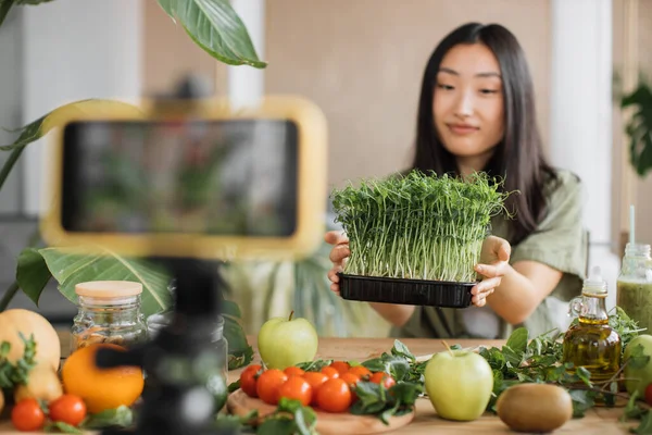 レシピについてのスマートフォンでビデオレッスンを記録する美しい若いアジアの女性ブロガーマイクログリーンもやしや有機新鮮な野菜や果物から健康的なサラダを調理する方法 — ストック写真
