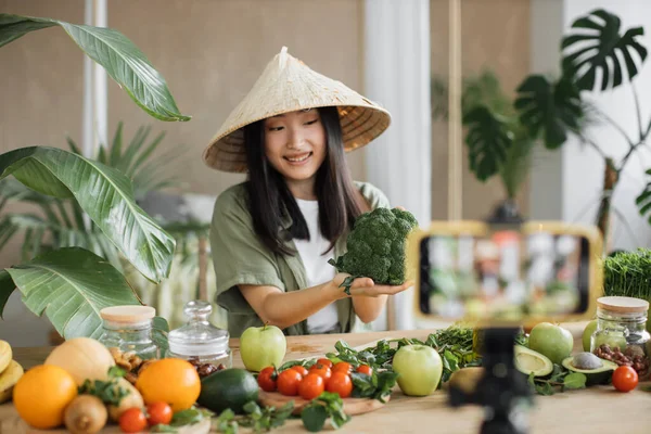 アジアの女性は 熱帯リゾートキッチンスタジオでソーシャルメディアのビデオコンテンツを作成する電話を使用して健康的な食べ物を作っています ブロッコリーを使用した美しい女性 健康的なサラダを準備野菜や果物 — ストック写真