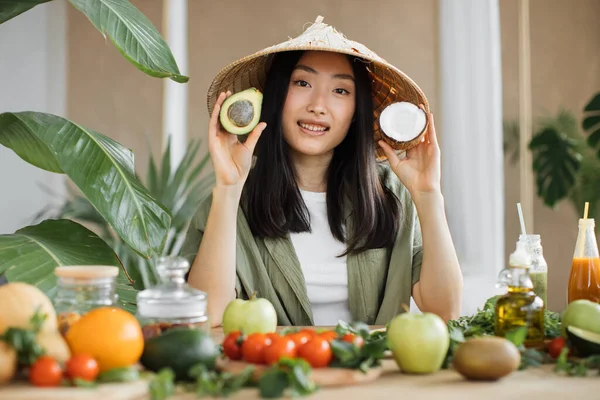 若いアジアの女性ブロガーやコンテンツ作成者の健康的なサラダを準備の顔に焦点を当てます ブログを記録しながら魅力的な女性はアボカドとココナッツを保持 — ストック写真
