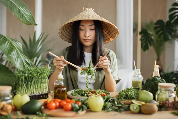 エキゾチックな光スタジオで屋内の葉を攪拌健康的なサラダを作る幸せな若い美しいアジアの女性 熱帯の家で健康食品 健康的なライフスタイルのコンセプト — ストック写真