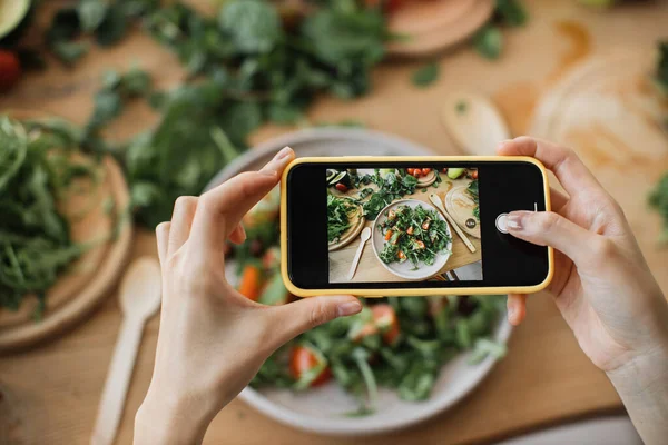 여자들은 손으로 음식이나 저녁의 사진을 찍습니다 샐러드 아보카도 토마토 네트워크를 — 스톡 사진