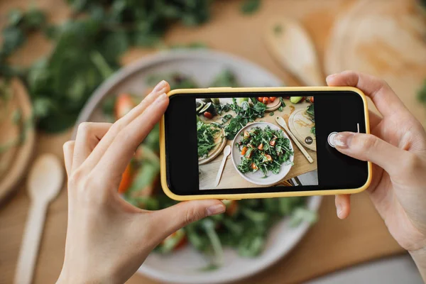 여자들은 손으로 음식이나 저녁의 사진을 찍습니다 샐러드 아보카도 토마토 네트워크를 — 스톡 사진