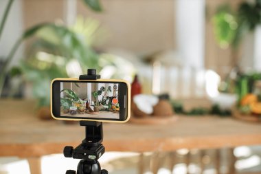 Blogcu ya da içerik yaratıcısı evde doğal kozmetik ürünleri hazırlıyor ve telefonda video kaydediyor. Kivi, portakal, naneli hindistan cevizi derisi ve kaplıca. Bir şişe yağ, bir kavanoz maske, kremalı bardak..