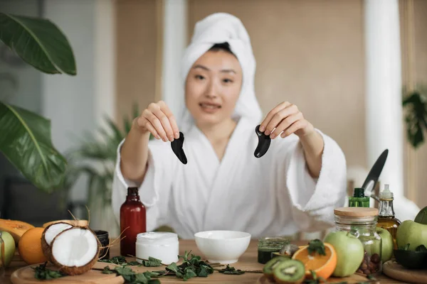수건을 머리에 테이블에 콜라겐 패치를 아시아인 여성의 집중하 이국적 화실에서 — 스톡 사진