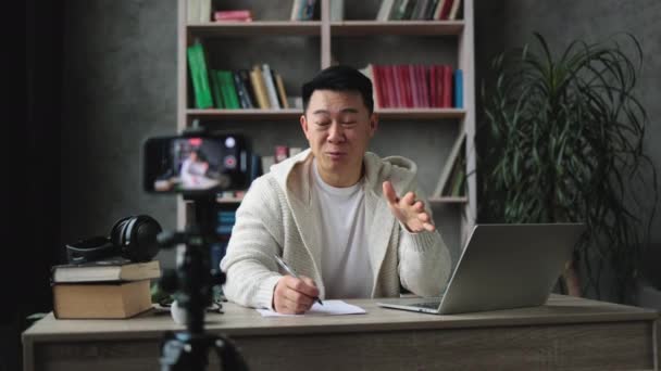 Sorrindo Asiático Homem Falando Gesticulando Frente Câmera Smartphone Moderno Escrevendo — Vídeo de Stock