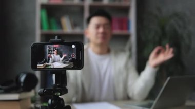 Çekici Asyalı serbest çalışan, gözleri kapalı bir şekilde oturmuş meditasyonla stresi nasıl azaltacağını kaydediyor. Rahatlama ve uyum kavramı, iş yerinde stres yok..