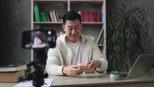 아시아 남자가 시계로 박스를 풀면서 라이브 스트림을 자신의 구독자들 가젯에 — 비디오
