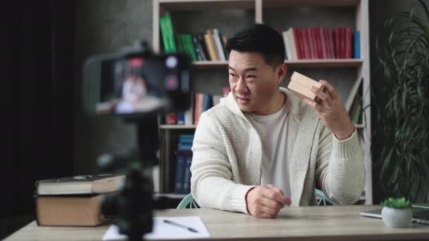 Sıradan Giyinen Yakışıklı Asyalı Adam Hediye Paketini Açarken Kameraya Kayıt — Stok video