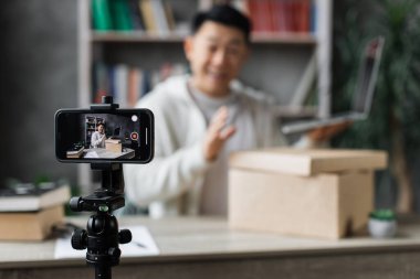 Yeni kablosuz dizüstü bilgisayarı olan kutuları açarken Asyalı genç adamın kameraya video kaydetmesine odaklan. Erkek nüfuzlu kişi, abonelerle yeni düzen hakkındaki olumlu görüşlerini paylaşıyor..