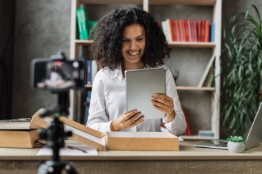 Çok kültürlü bir kadın, yeni kablosuz tabletle birlikte kutuları açarken kameraya video kaydediyor. Abonelerle kadın etkileri paylaşan kişi, yeni düzen hakkındaki olumlu görüşlerini paylaşıyor.