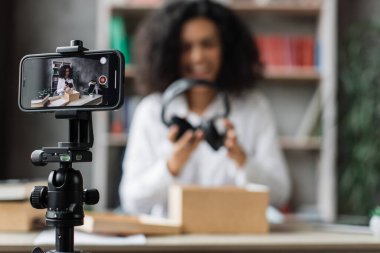 Akıllı telefon ekranına odaklan. Yeni kablosuz kulaklıklarla kutuları açarken kameraya video kaydeden kadın. Abonelerle kadın etkileri paylaşan kişi, yeni düzen hakkındaki olumlu görüşlerini paylaşıyor.