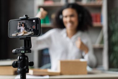 Ekrana odaklan, genç çok uluslu kadın telefon kamerasıyla video kaydederken yeni kablosuz kulaklıklarla kutuları açıyor..