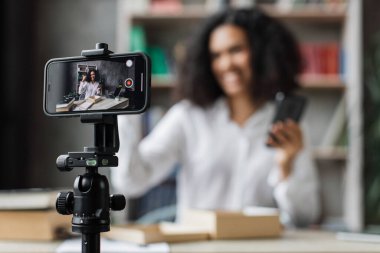 Akıllı telefon ekranına odaklan. Modern telefon kamerasıyla video çeken çok uluslu hoş bir kadın. Paket kutusunu yeni akıllı telefonuyla açıyor. İnsan kavramı, teknoloji ve blog yazma.